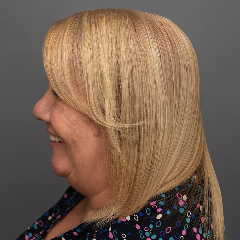 Profile view of a woman with long blonde hair smiling against a gray background.