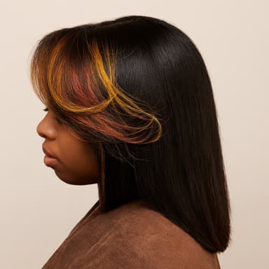 Profile of woman with straight black hair highlighted with orange and yellow tones, wearing a brown top against beige background