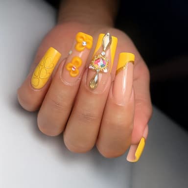 Stylish yellow nails with decorative designs and gems.